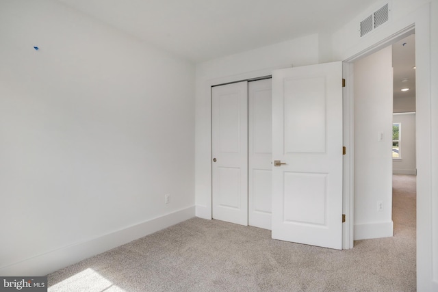 unfurnished bedroom with light colored carpet and a closet