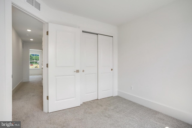 unfurnished bedroom with light colored carpet and a closet