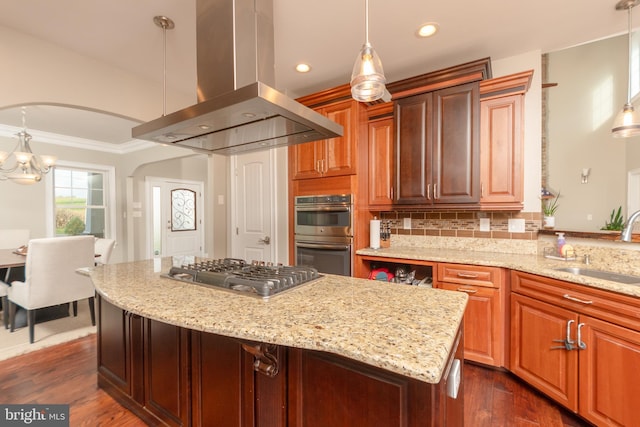 kitchen featuring sink, appliances with stainless steel finishes, pendant lighting, island exhaust hood, and light stone countertops