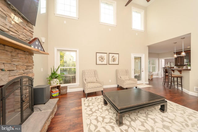 living room with a stone fireplace, dark hardwood / wood-style floors, and a healthy amount of sunlight