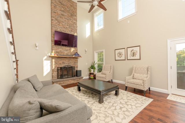 living room with hardwood / wood-style flooring, a stone fireplace, and ceiling fan