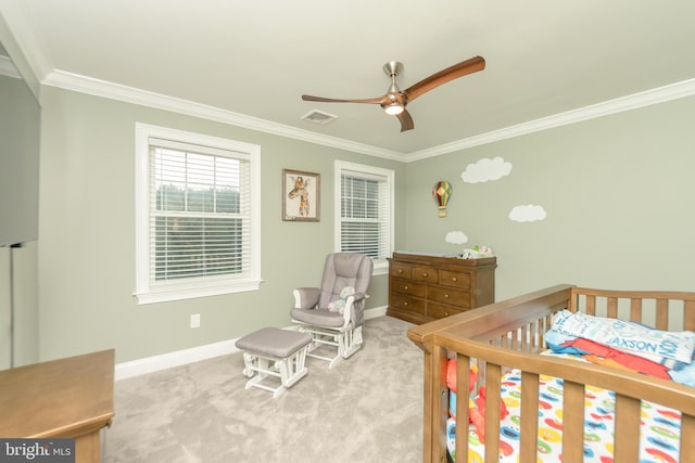 bedroom with crown molding, light colored carpet, a nursery area, and ceiling fan