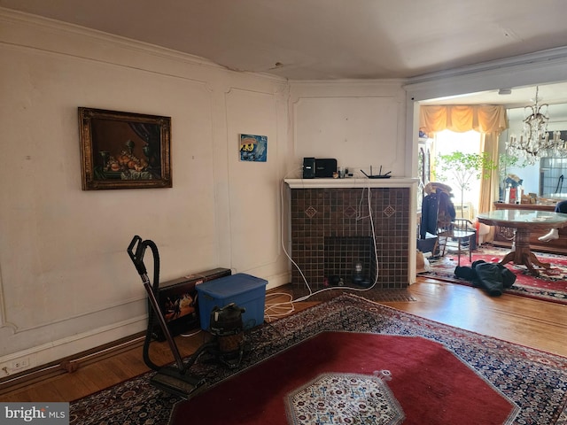 interior space featuring a notable chandelier, hardwood / wood-style flooring, ornamental molding, and a tile fireplace