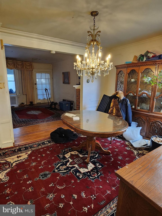 dining area featuring ornamental molding, hardwood / wood-style floors, and an inviting chandelier