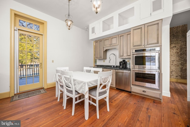 kitchen with appliances with stainless steel finishes, dark hardwood / wood-style floors, sink, and decorative light fixtures