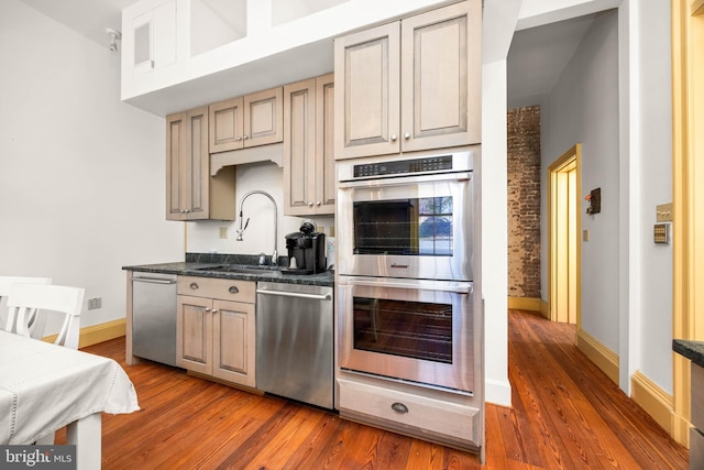 kitchen featuring dark wood-type flooring, stainless steel appliances, sink, and dark stone countertops