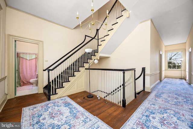 staircase with wood-type flooring and a notable chandelier