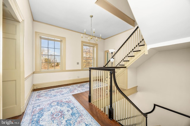 stairway featuring an inviting chandelier, hardwood / wood-style flooring, and crown molding