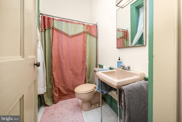 full bathroom featuring shower / tub combo with curtain, tile patterned floors, toilet, and sink