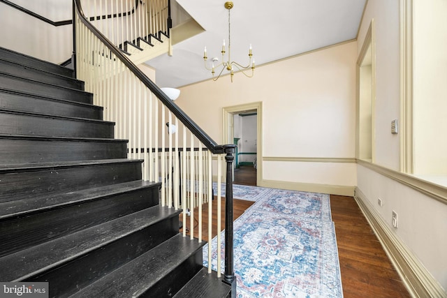 staircase with an inviting chandelier, hardwood / wood-style flooring, and ornamental molding