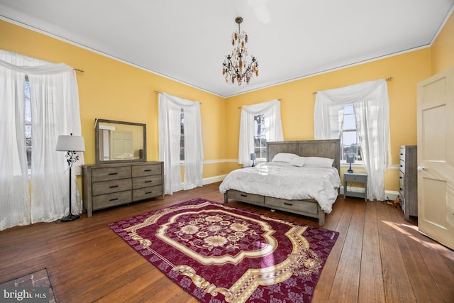 bedroom with ornamental molding, hardwood / wood-style floors, and a notable chandelier