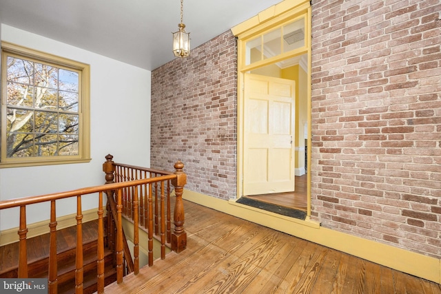 corridor with brick wall and hardwood / wood-style floors