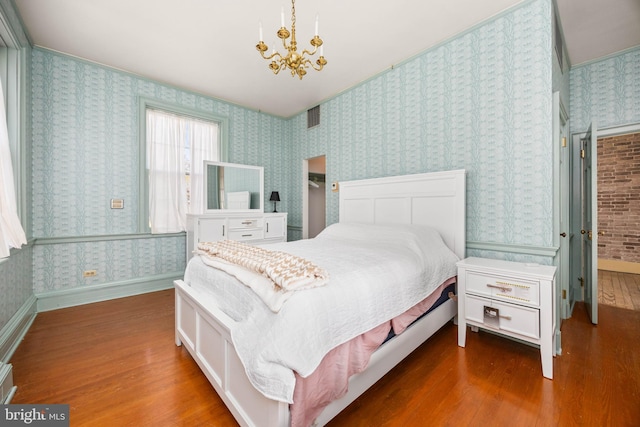 bedroom with dark hardwood / wood-style floors and a notable chandelier