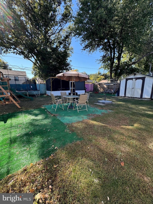 view of yard with a playground, a trampoline, and a shed