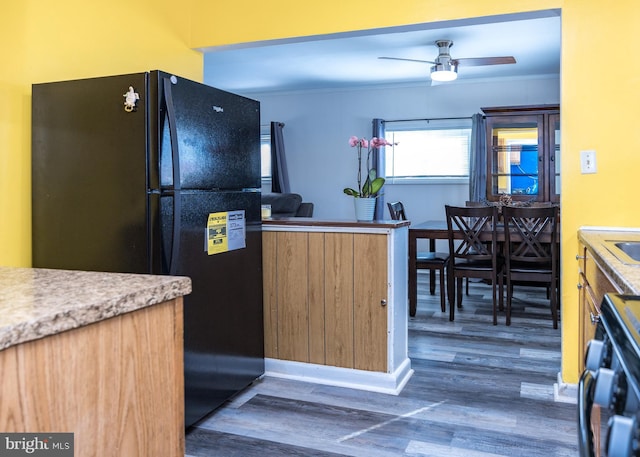 kitchen featuring black refrigerator, dark hardwood / wood-style flooring, ornamental molding, stove, and ceiling fan