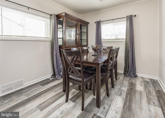 dining area featuring wood-type flooring and ornamental molding