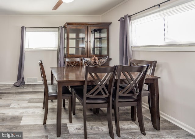 dining space with hardwood / wood-style flooring, crown molding, and ceiling fan