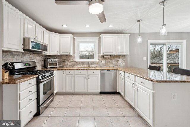 kitchen with appliances with stainless steel finishes, decorative light fixtures, sink, white cabinets, and kitchen peninsula