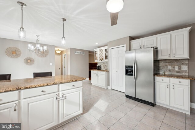 kitchen featuring pendant lighting, tasteful backsplash, white cabinetry, stainless steel fridge, and light tile patterned floors