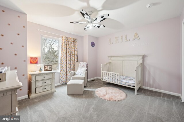 bedroom featuring a nursery area, ceiling fan, and carpet floors