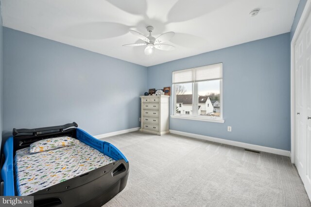 carpeted bedroom with ceiling fan and a closet