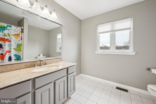 bathroom with vanity, tile patterned flooring, toilet, and a healthy amount of sunlight