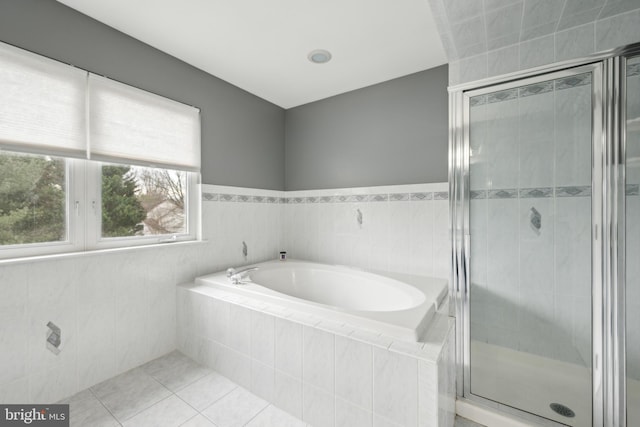 bathroom featuring tile patterned flooring, independent shower and bath, and tile walls