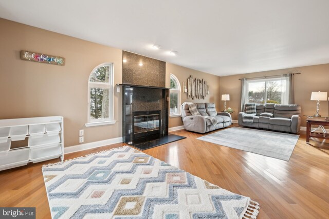 living room with wood-type flooring and a tiled fireplace