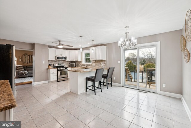 kitchen with a breakfast bar, appliances with stainless steel finishes, backsplash, white cabinets, and kitchen peninsula