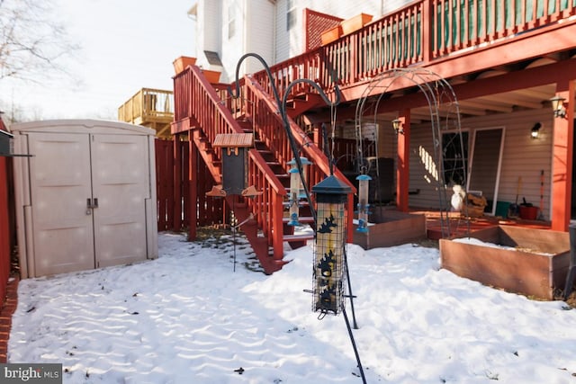 snow covered property featuring a shed and a wooden deck