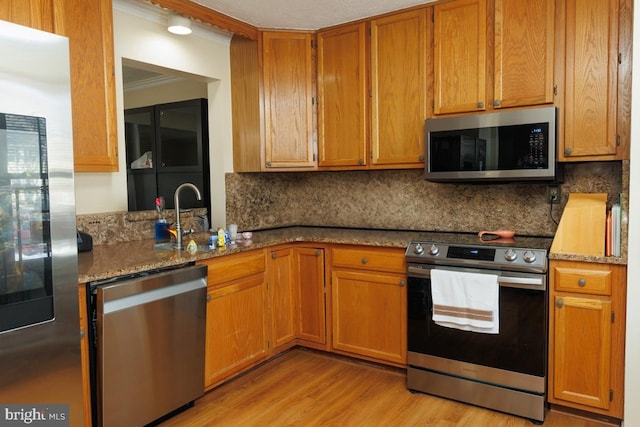 kitchen with light stone countertops, appliances with stainless steel finishes, light hardwood / wood-style floors, and decorative backsplash