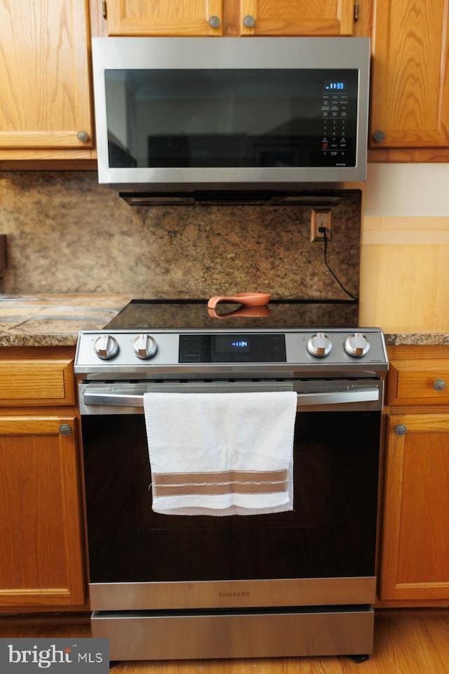 kitchen with stainless steel appliances, light stone countertops, and decorative backsplash