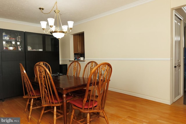 dining area featuring crown molding, a chandelier, a textured ceiling, and light wood-type flooring