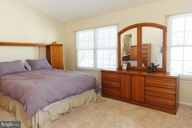 bedroom featuring multiple windows, vaulted ceiling, and light carpet