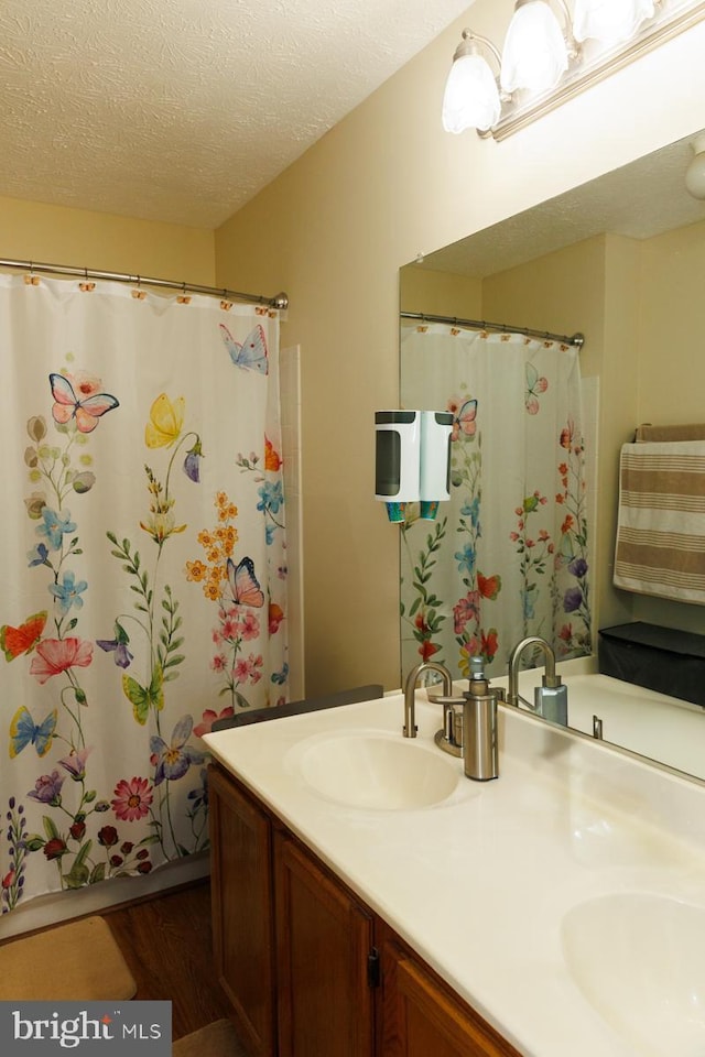 bathroom with wood-type flooring, curtained shower, a textured ceiling, and vanity