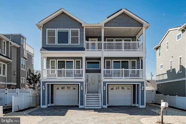 beach home featuring a balcony, a garage, fence, and decorative driveway