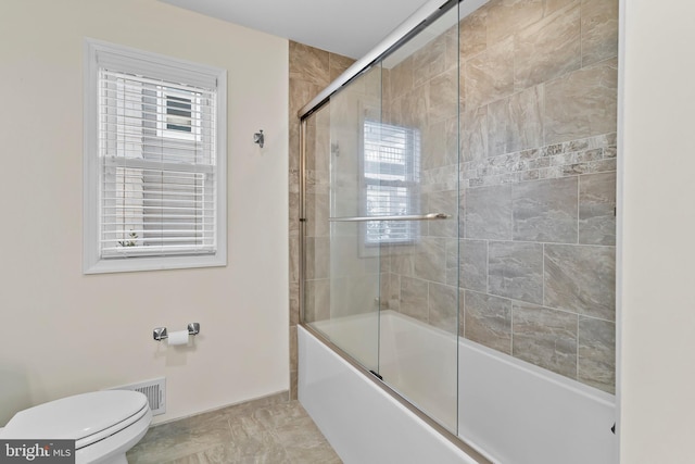 bathroom featuring toilet, visible vents, and combined bath / shower with glass door