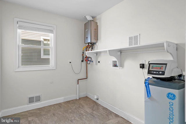 laundry area with tankless water heater, hookup for a gas dryer, laundry area, visible vents, and baseboards