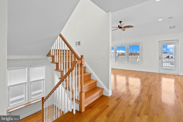 stairway featuring baseboards, visible vents, ceiling fan, and wood finished floors