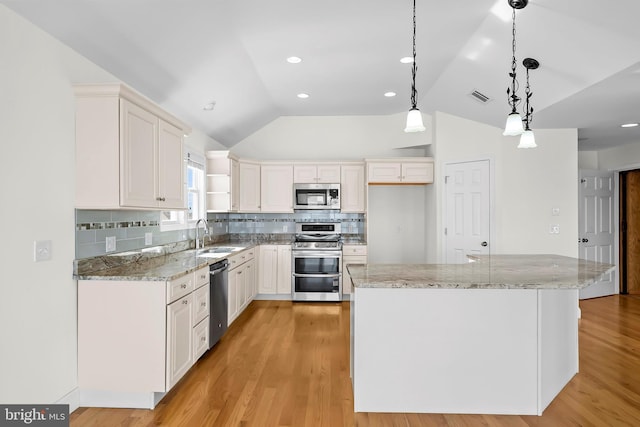 kitchen with stainless steel appliances, lofted ceiling, visible vents, white cabinetry, and a sink