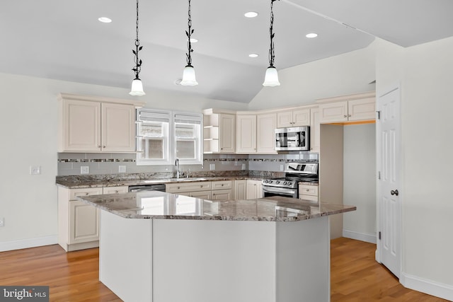 kitchen featuring appliances with stainless steel finishes, light wood-style floors, decorative backsplash, and light stone countertops