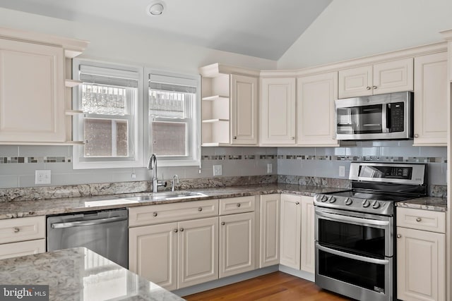 kitchen featuring vaulted ceiling, appliances with stainless steel finishes, open shelves, and a sink