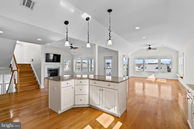 kitchen featuring visible vents, lofted ceiling, open floor plan, decorative light fixtures, and light wood-style floors