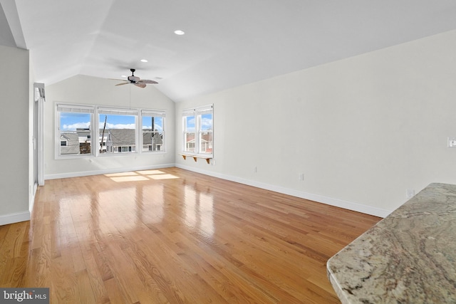 living room featuring lofted ceiling, a ceiling fan, light wood-style flooring, and baseboards