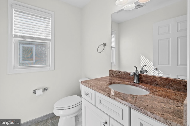 half bathroom featuring toilet, tile patterned floors, and vanity