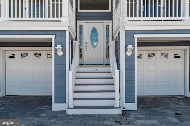 property entrance featuring decorative driveway, an attached garage, and a balcony