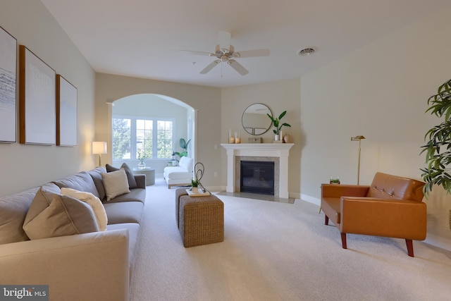 living room featuring light carpet, a tile fireplace, and ceiling fan