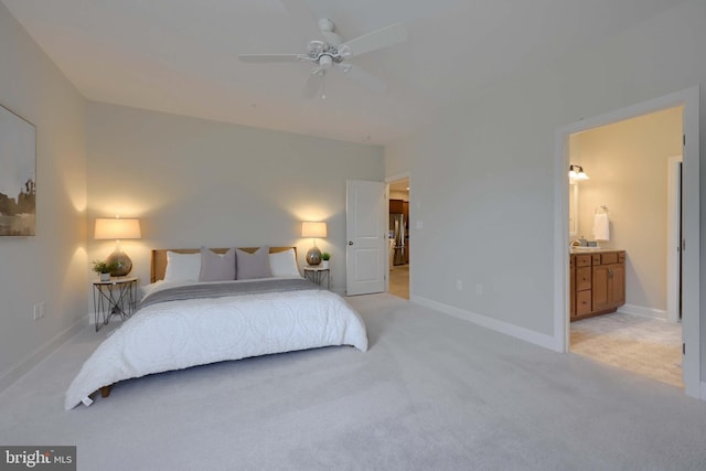 bedroom featuring ceiling fan, sink, light carpet, and ensuite bath