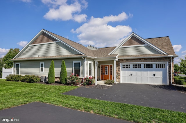 view of front of house featuring a garage, central AC unit, and a front yard