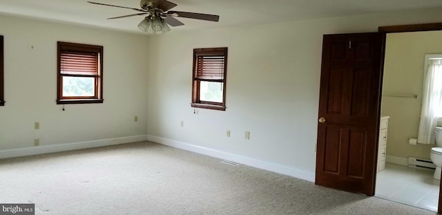 carpeted spare room with ceiling fan, plenty of natural light, and a baseboard heating unit